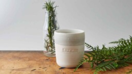 Clement &Amp; Claude Candle On Wooden Table With Rosemary And Fern